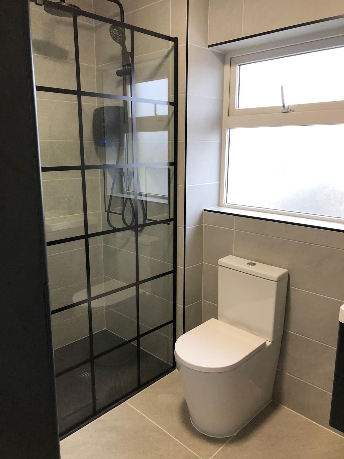 Black crittall-style walk-in shower screen with slate grey tray and greige tiling