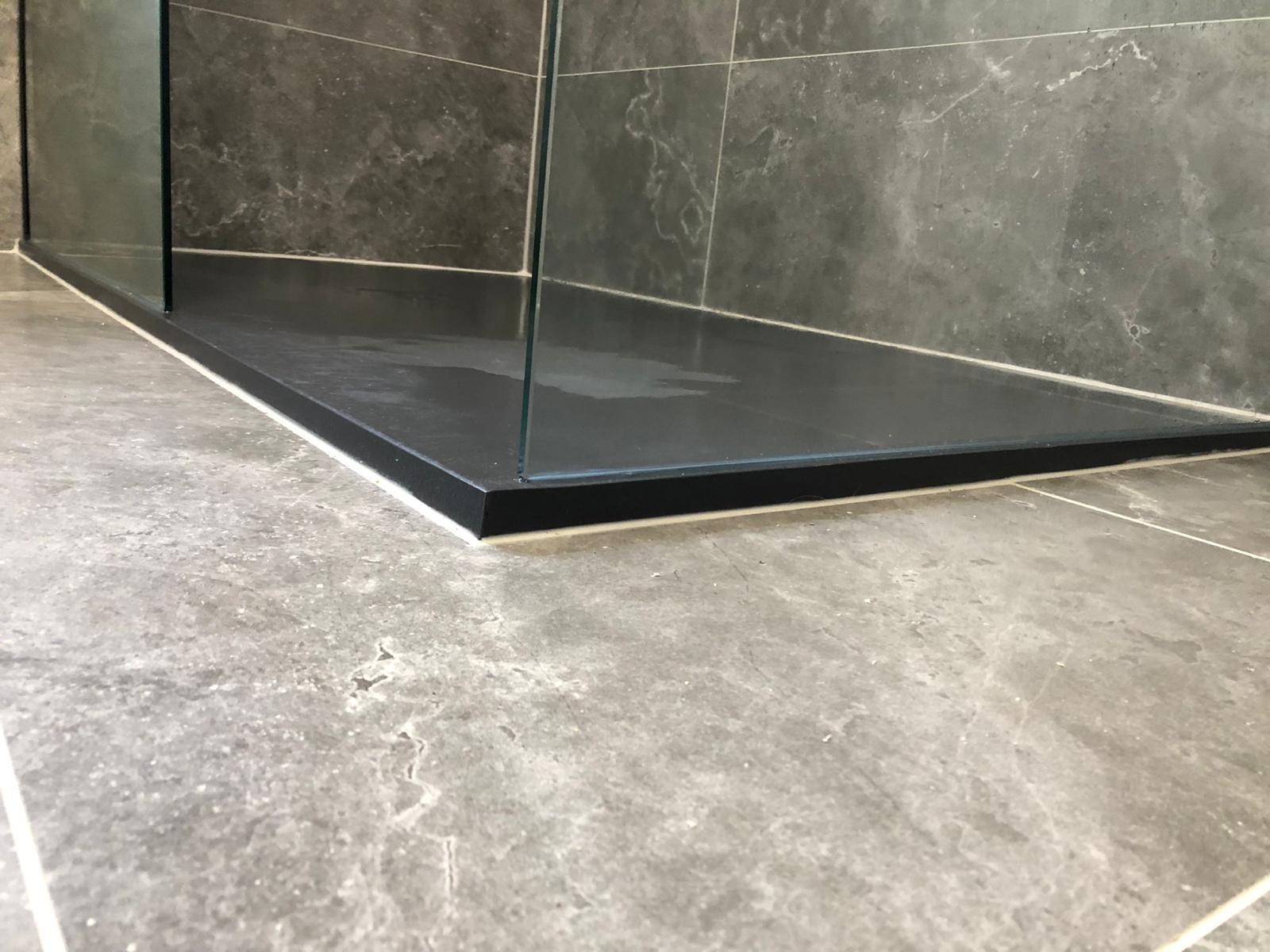 Slimline black shower tray sitting flush with the grey marble-effect floor tiles