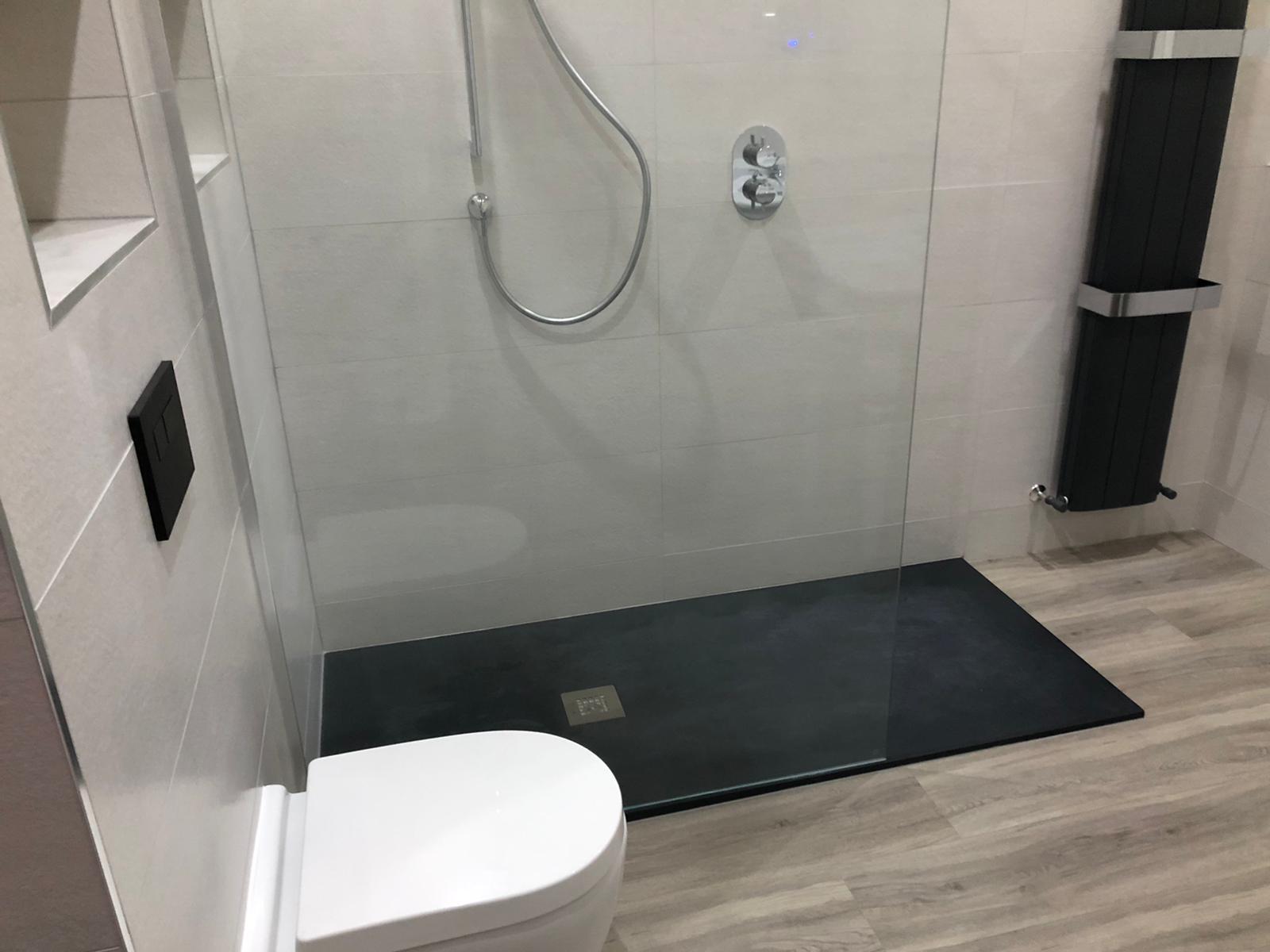 Slate grey slimline tray and frameless screen meeting wood-effect plank flooring