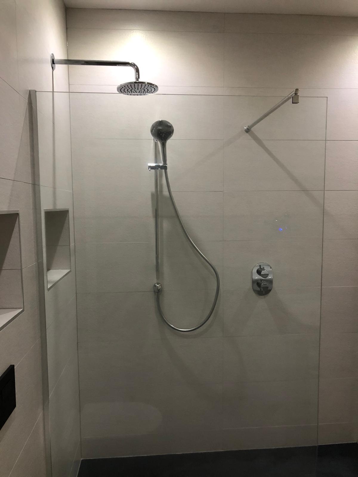 Chrome rain head and riser rail with concealed thermostatic valve in the walk-in shower