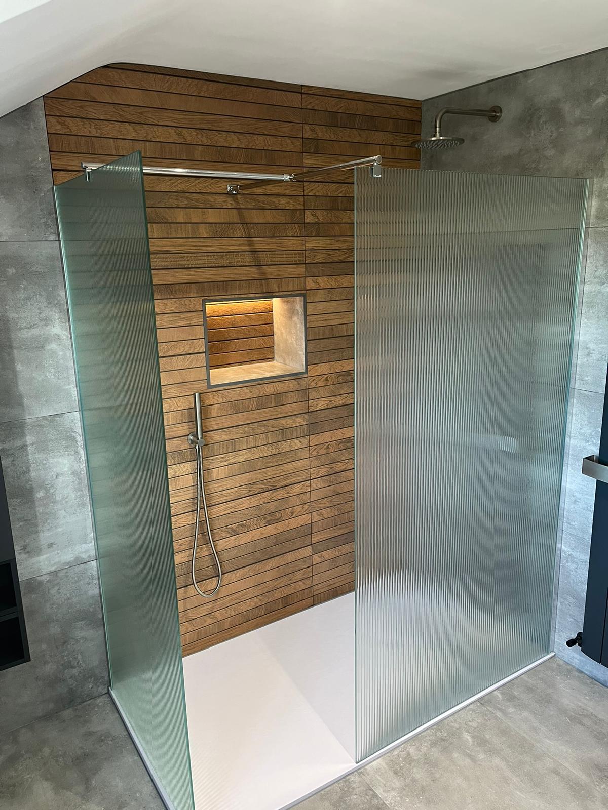 Walk-in wet room with oak slat-effect porcelain, reeded glass screens and lit niche