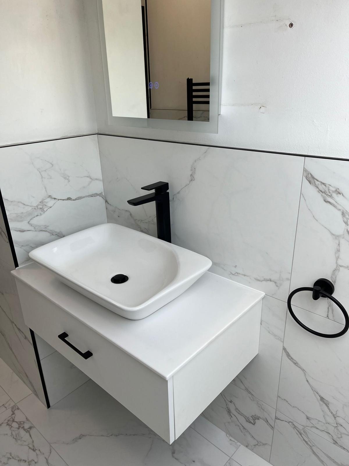 Counter-top basin on a wall-hung white vanity with matt black tall tap and marble-effect tiling