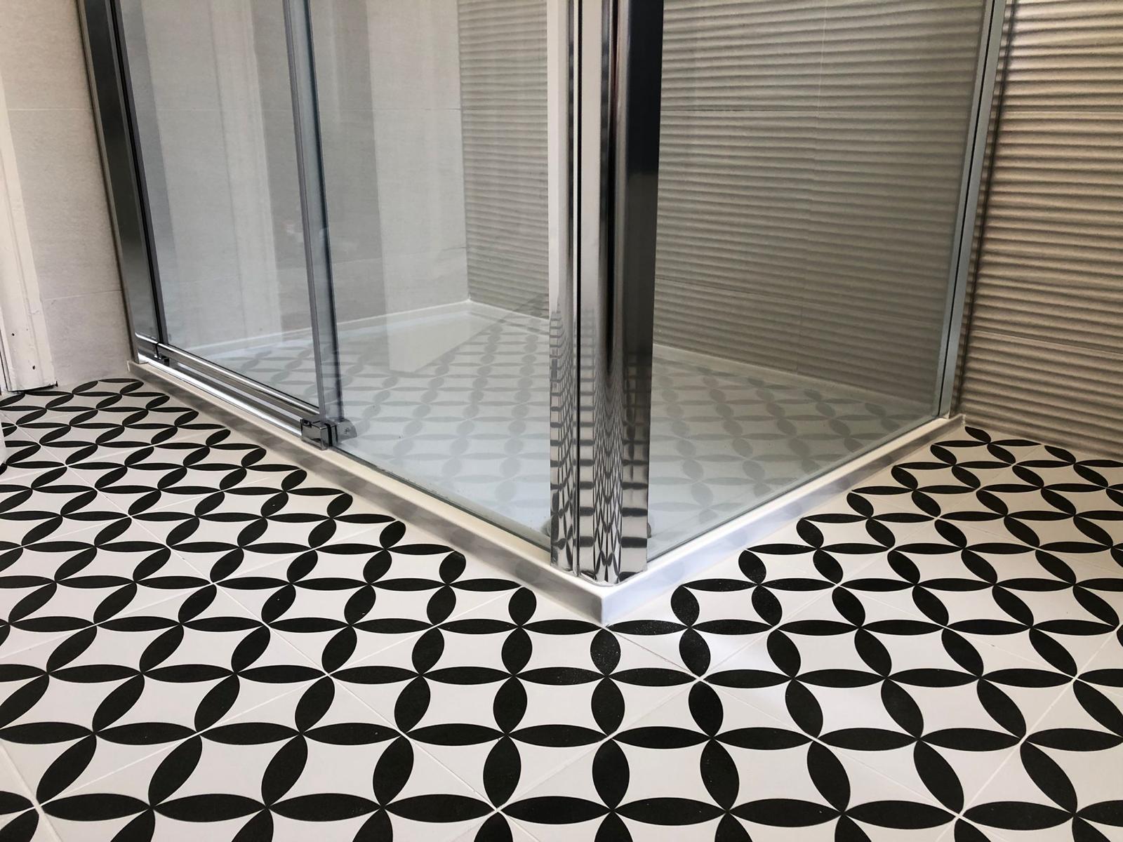 Chrome framed sliding shower enclosure with low-profile tray meeting the patterned floor tile