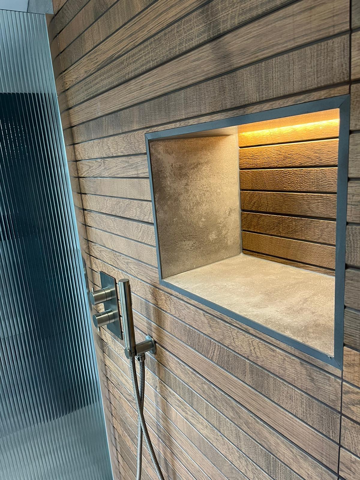 Brushed nickel wall-mounted rain shower head against oak slat-effect tiling