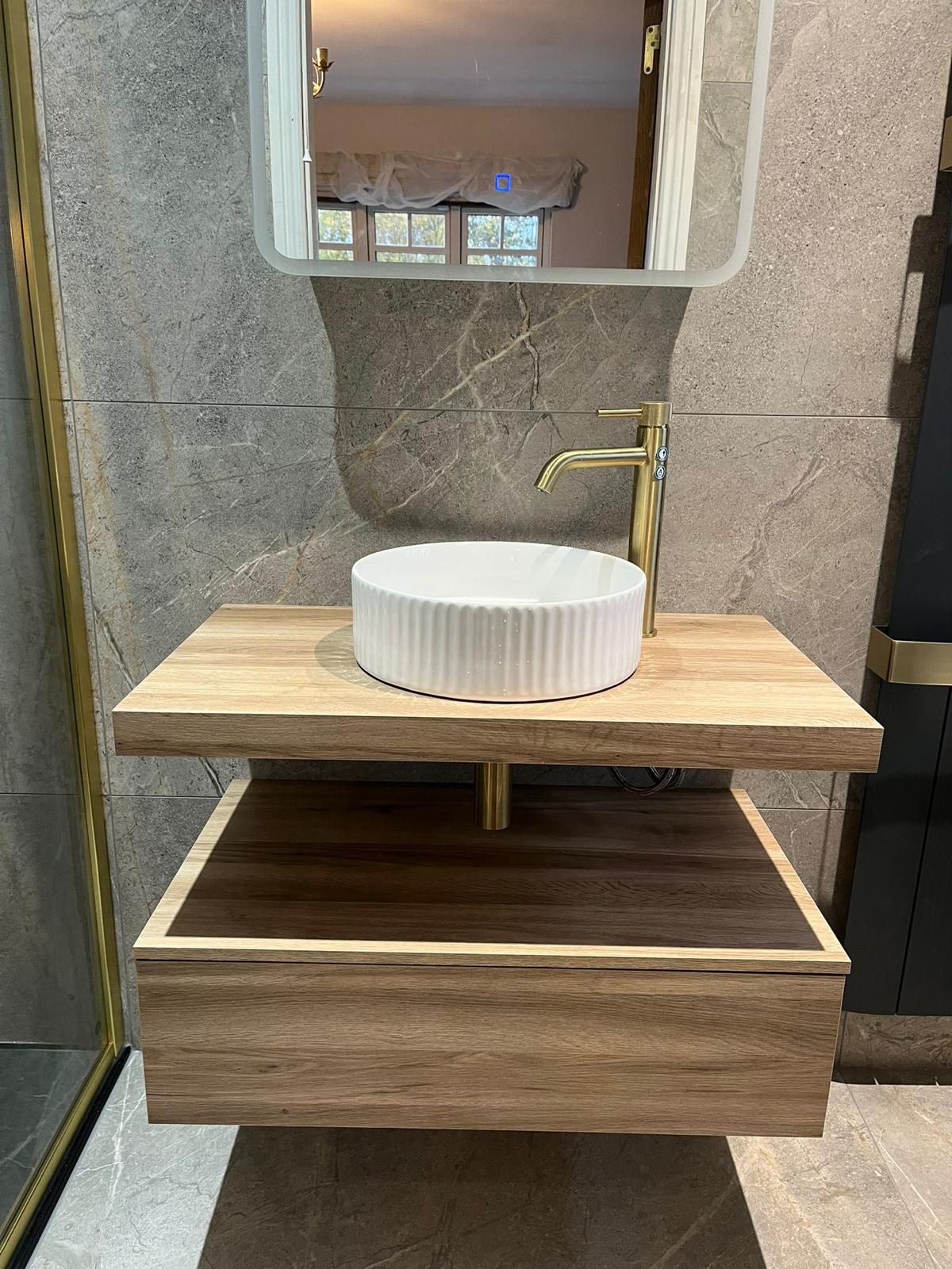 Fluted countertop basin with brushed brass tall tap on an oak shelf