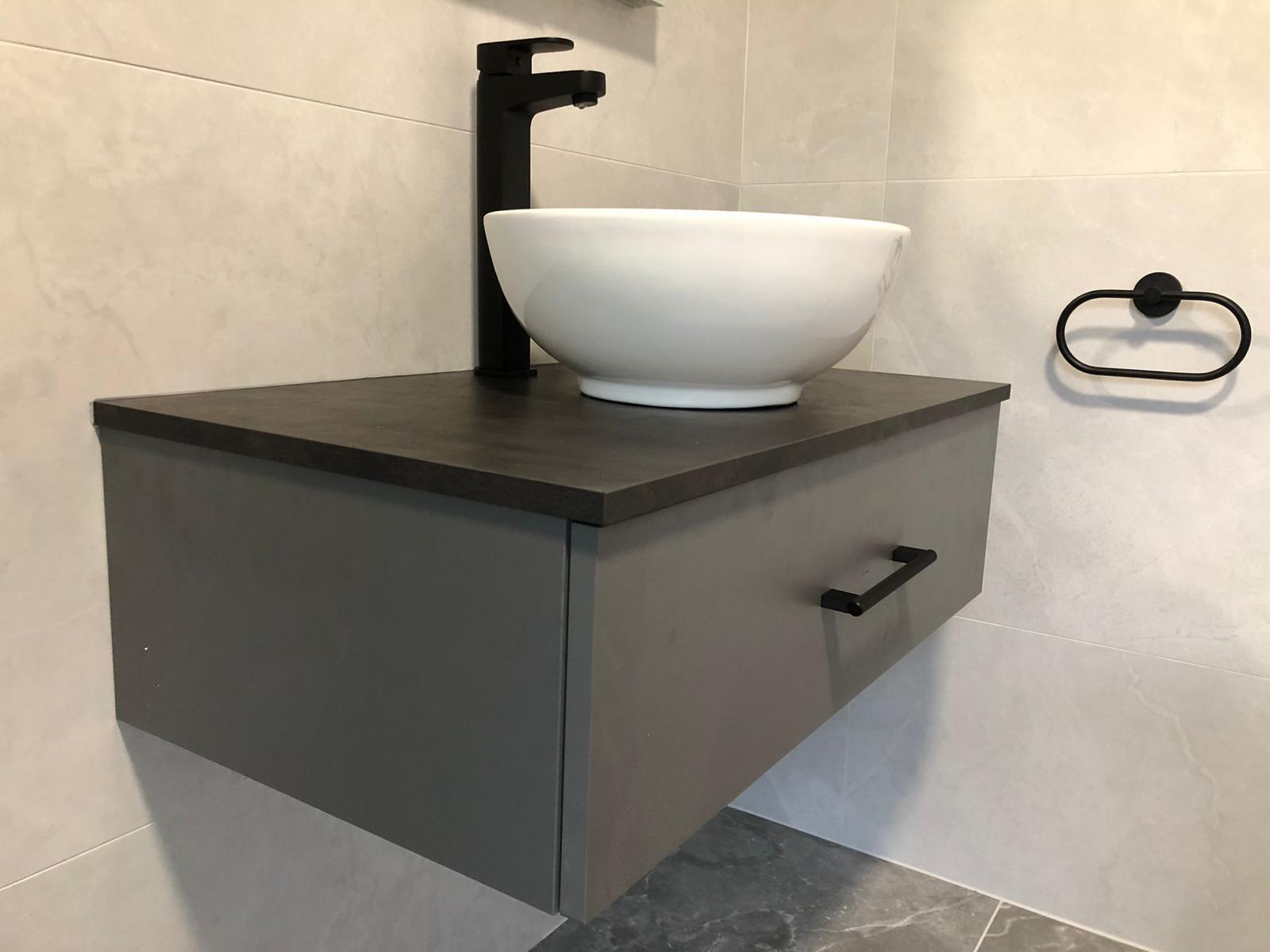 Close-up of the stone-effect vanity top, ceramic bowl basin and black towel ring
