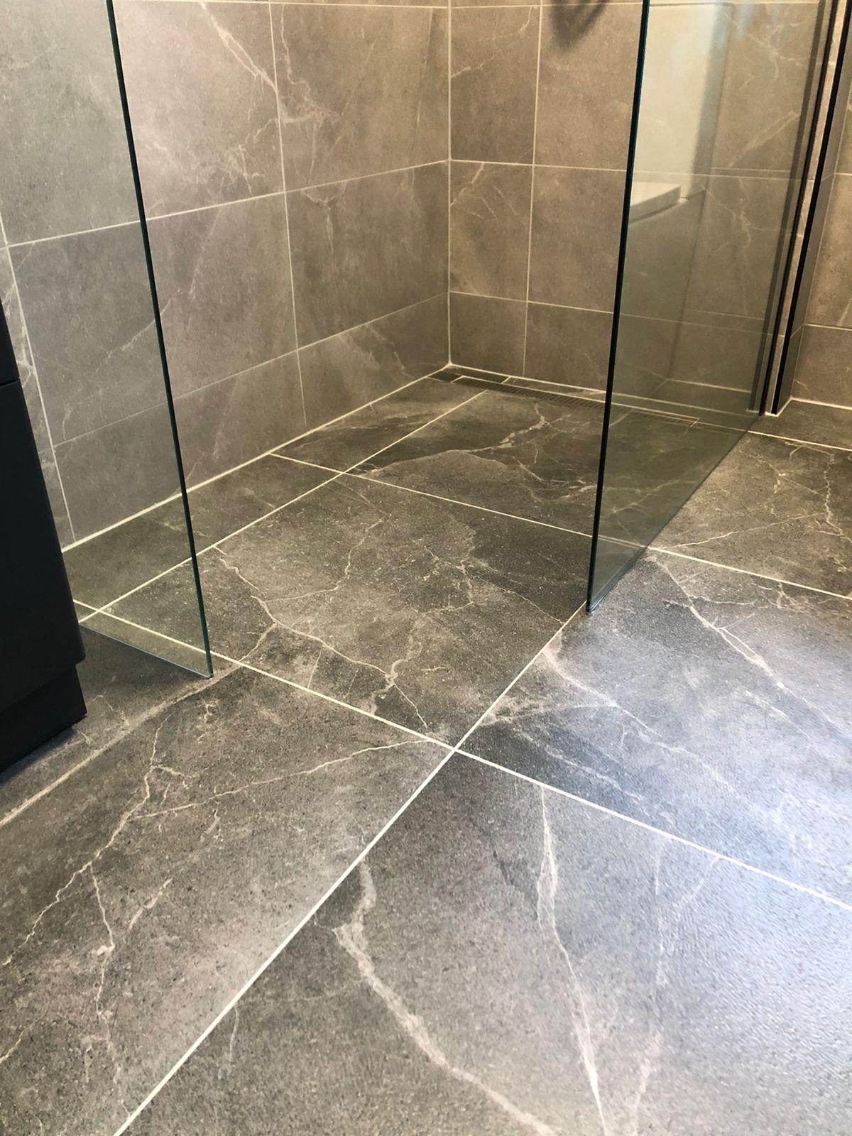 Detail of the linear shower drain and stone-effect floor tiles laid to fall