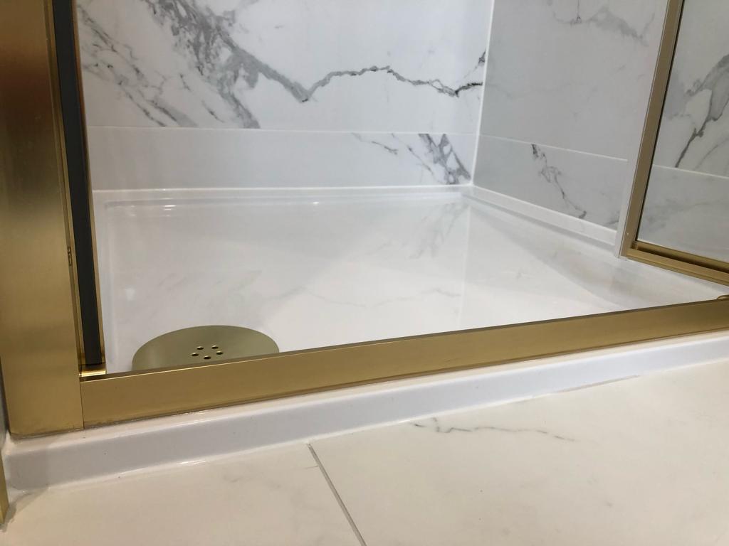 Brass-framed shower enclosure with marble tray and matching brass waste cover