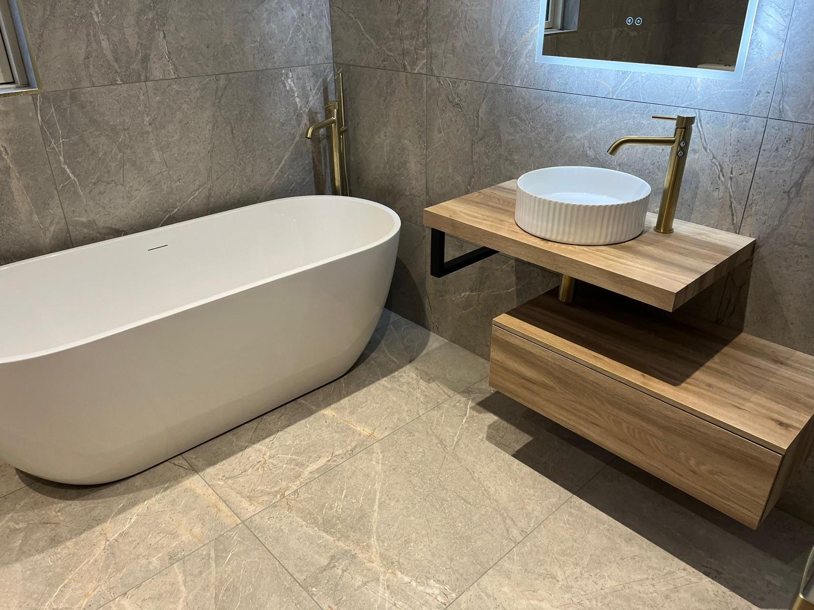 Freestanding bath and oak vanity in a marble-effect ensuite fitted by Plan B