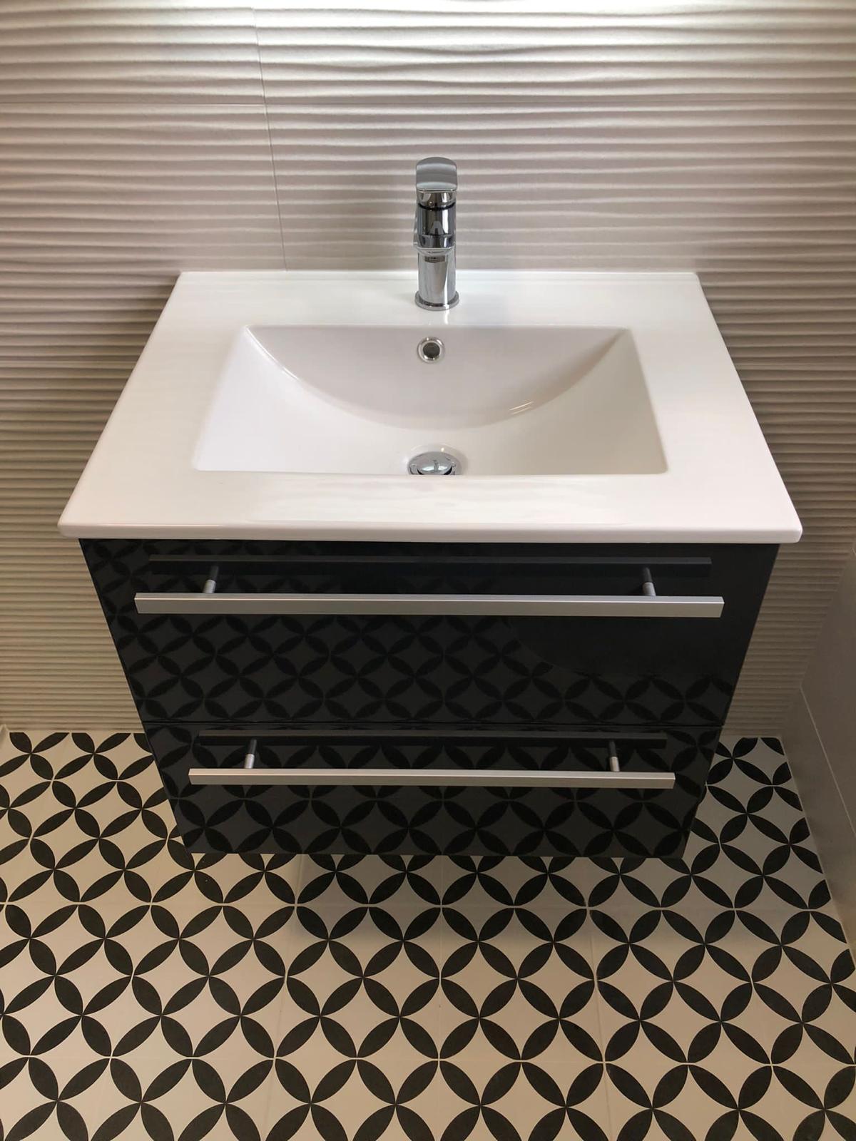 Gloss black wall-hung vanity with ceramic basin and chrome mixer above a monochrome patterned floor