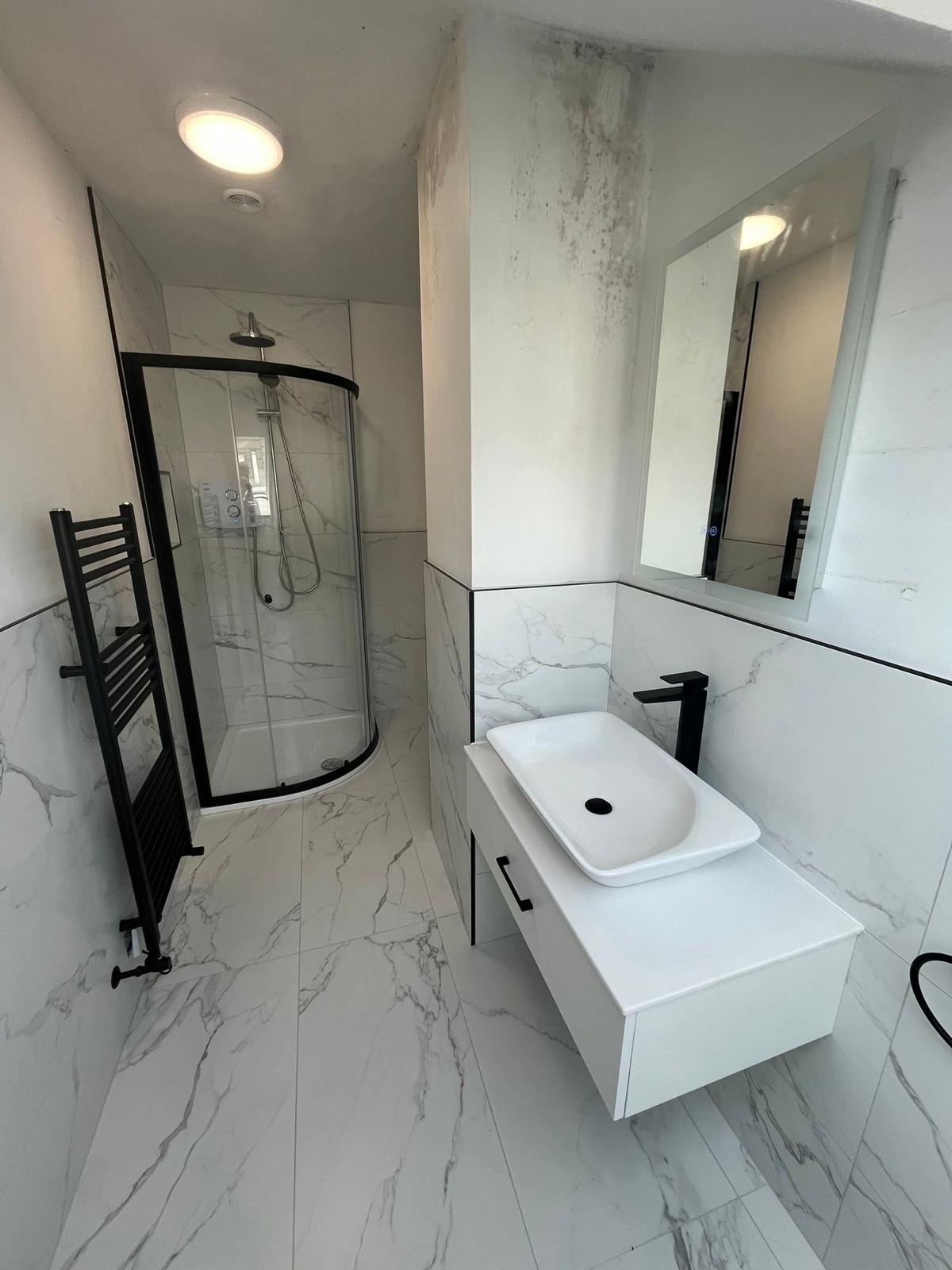 Compact bathroom with statuario-effect porcelain, quadrant shower enclosure and black ladder radiator