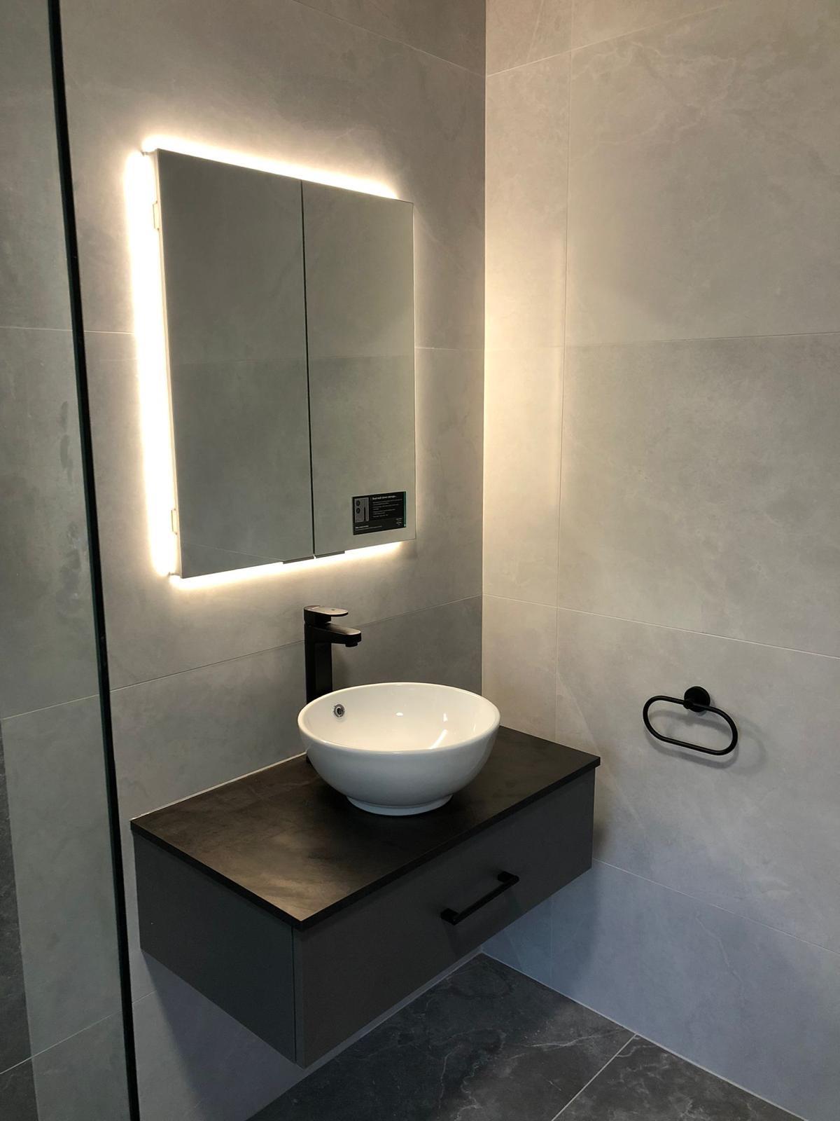 Graphite wall-hung vanity with round counter-top basin, tall black mixer and backlit mirrored cabinet