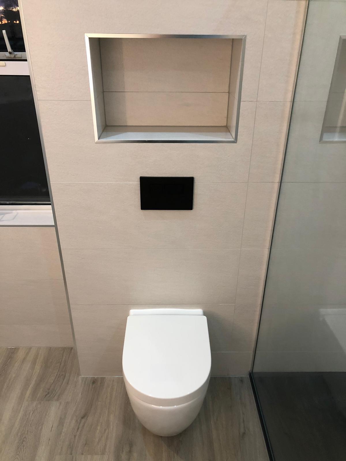 Wall-hung rimless WC with matt black flush plate and a chrome-trimmed recessed niche