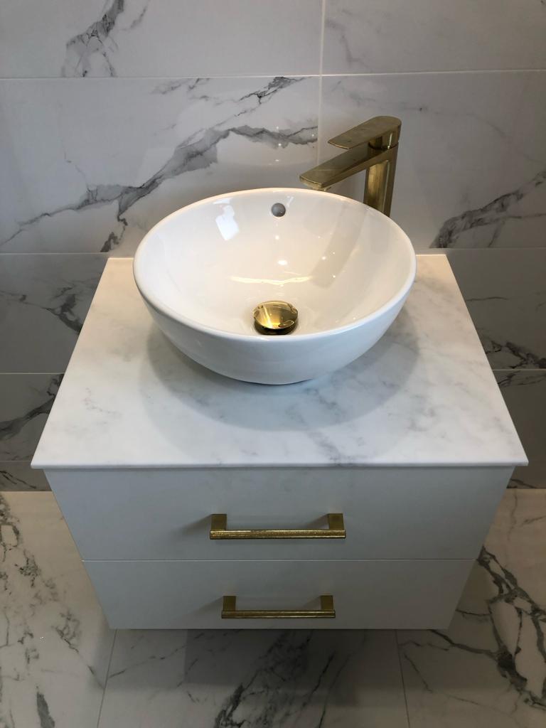 Wall-hung vanity with marble top, round counter-top basin and tall brushed brass mixer