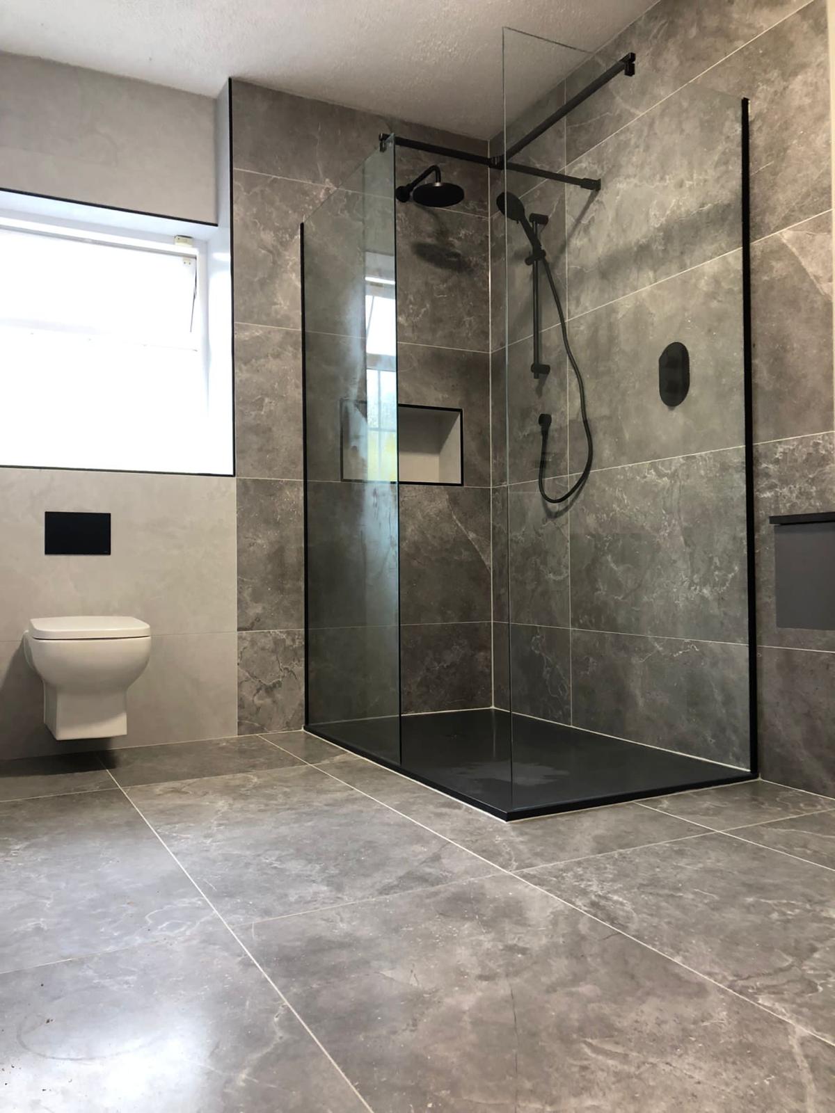 Frameless walk-in shower on a slate black tray with grey marble-effect porcelain walls
