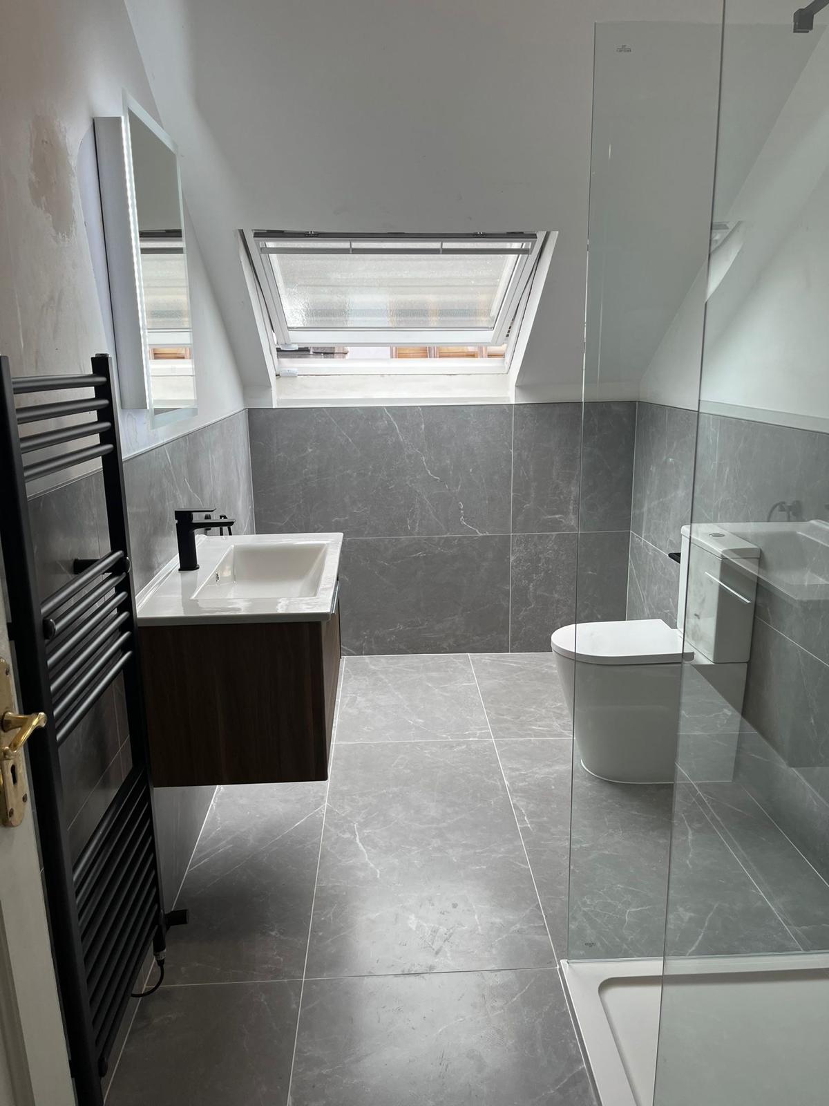 Loft ensuite with grey marble-effect tiles, walnut vanity and frameless walk-in shower