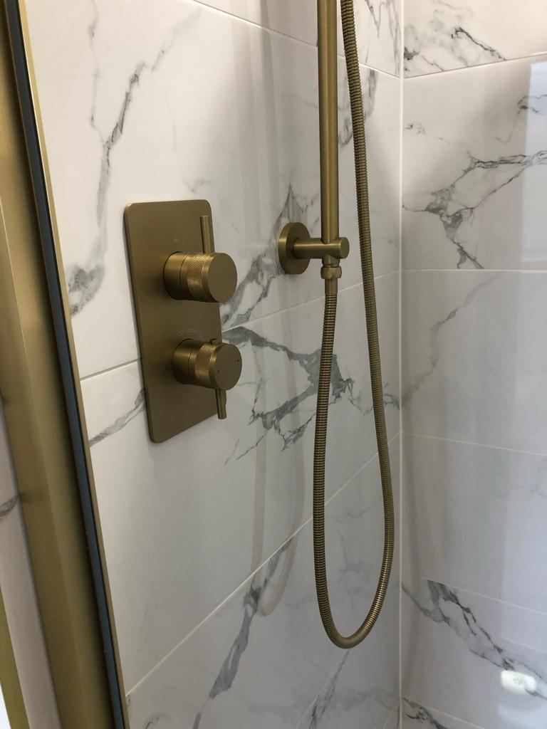 Knurled brushed brass concealed shower valve and riser rail on marble-effect tile