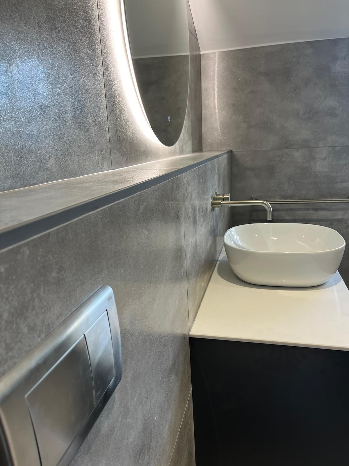 Counter basin with brushed nickel wall-mounted tap and brushed steel flush plate